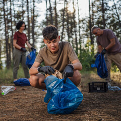 family of volunteers men woman pick up waste garbage to clean forest