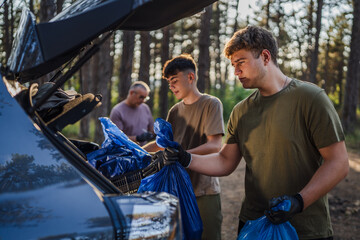 teenagers young men pack waste garbage in the trunk of a car