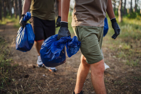unknown volunteers pick up waste garbage and walk through from forest