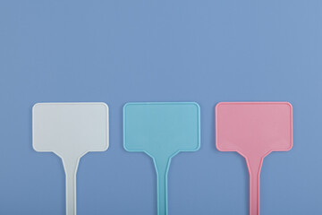 Three colored plastic plant markers on blue background. Labels or sings as templates or design...