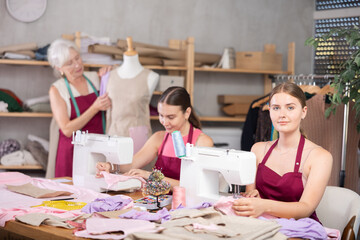 Family business, production of clothes - tailor showroom. Woman and girl tailors sewing, senior female designer work with mannequin. 