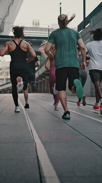 Rear view athletes runners train in the stadium. Young team of man and woman in sportswear and shoes. Like-minded club