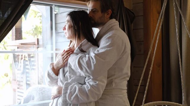Mature couple in a white bathrobes hugging each other kissing at home room. Intimate Moment. Tender embrace shared between a loving middle age man and woman, husband and wife. Deep love. Vacation