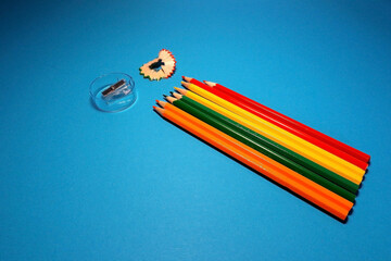 Colorful pencils with pencil sharpener and wood shaving on blue background. Creative back to school...