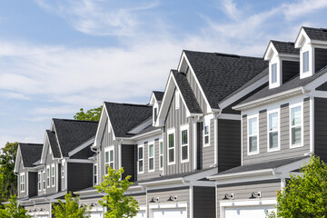 Detail of a row of grey and white modern farmhouse townhomes with board and batten and horiztonal...