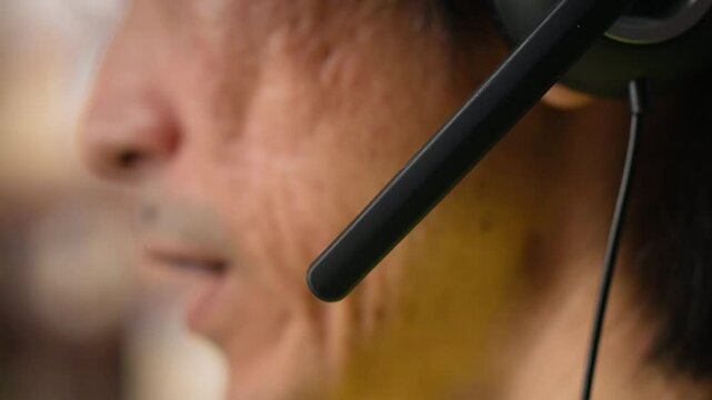 Close up of male staff answers help line calls in a logistics depot, updating clients on orders and resolving cargo mix ups. Managing tracking software for delivery route details. Camera B.