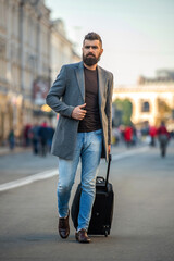 Business man in business trip. Stylish businessman crossing street with travel bag, lifestyle....