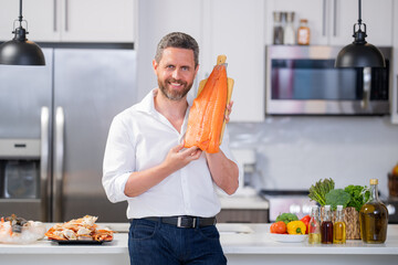 Man with raw salmon fillet at kitchen. Chef cooking a fish fillet. The big salmon is in the hands...