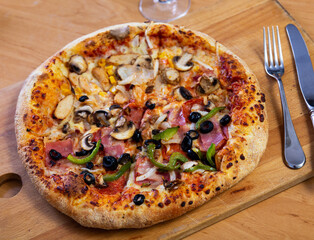 Double pizza with different ingredients in two halves served on wooden cutting board