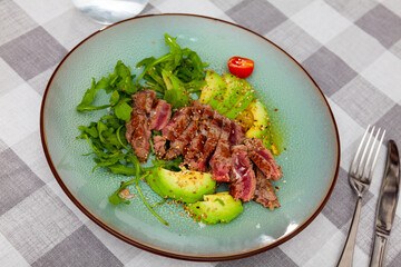 Delicious fried beef with avocado, parsley, sesame and tomatoes