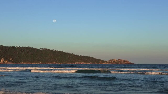 waves crashing on tropical beach with full moon over island 
