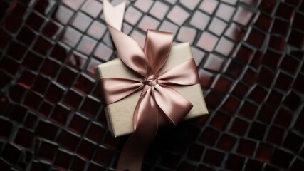 Elegant gift box with rose gold ribbon on a mosaic tile background in a video - Powered by Adobe