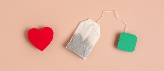 Tea bag and paper heart on beige background