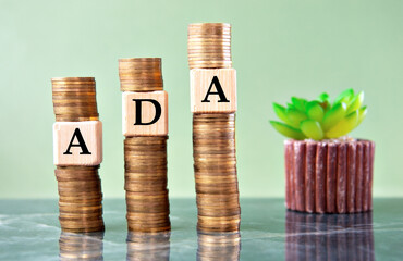 ADA - acronym on wooden cubes on stacks of coins