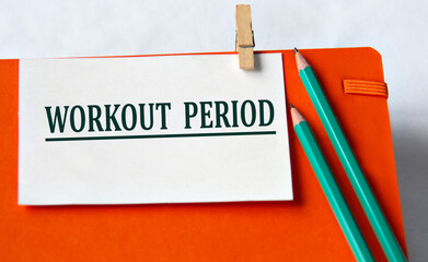 WORKOUT PERIOD - words on a white sheet on an orange notebook and pencils
