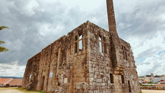 The Ruins of the Paco dos Condes de Barcelos Palace reveal broken stone galleries ivy draped arches and a medieval window traceried against the sky in Guimaraes, Portugal