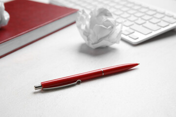 Pen, crumpled paper ball, notebook and keyboard on light background, closeup. World Poetry Day...