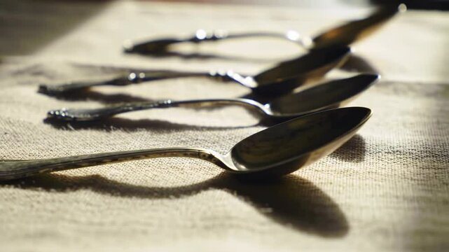 Row of antique spoons on rustic linen cloth, shallow depth of field