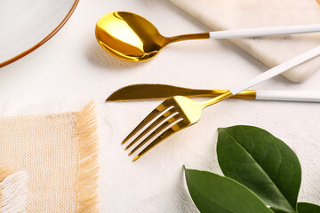 Plate with golden cutlery on white background