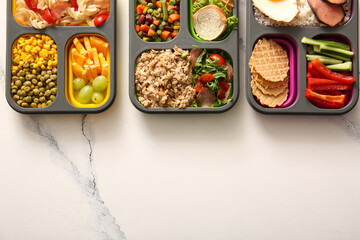 Lunchboxes with different delicious food on grunge white background