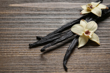 Aromatic vanilla sticks and flowers on wooden background