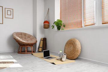 Laptop with sneakers and sports water bottle on mat in living room