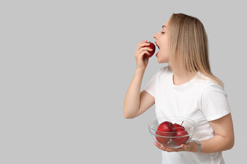 Young woman with apples on light background