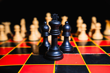 Chess pieces on a red and black board with black background