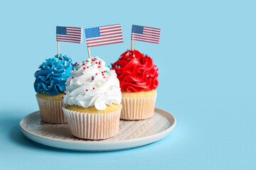 Tasty patriotic cupcakes with USA flags on blue background. American Independence Day