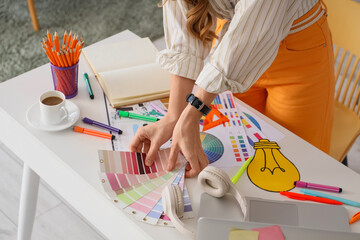 Female web designer with color palettes working at table in office, closeup