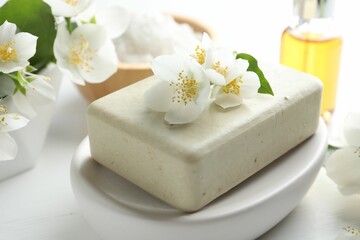 Soap bar, sea salt, essential oil and jasmine flowers on white wooden table, closeup