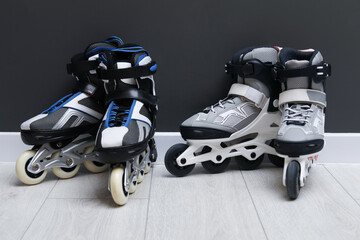 Pairs of roller skates on floor near black wall