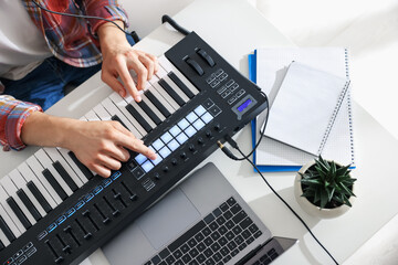 Man working with MIDI keyboard at white table indoors, above view