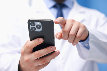Doctor with smartphone in clinic, closeup. Online medical consultation