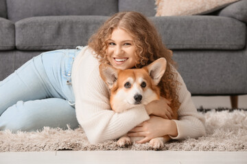 Young woman lying on floor and hugging cute Corgi dog in living room