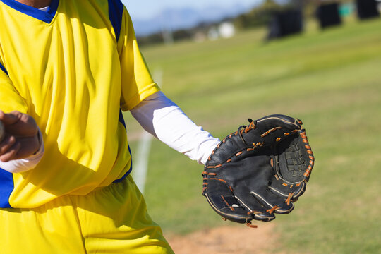 Senior baseball player standing on grass infield holding glove near chalk foul line, copy space