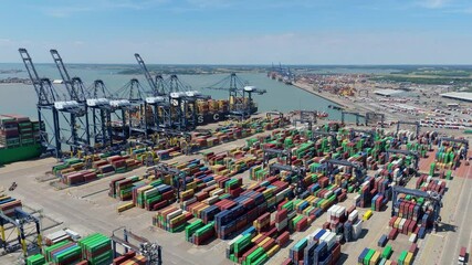 Aerial drone shot Felixstowe busy port cargo ships, shipping containers, huge cranes, loading and unloading heavy goods vehicles summer maritime business England UK - Powered by Adobe