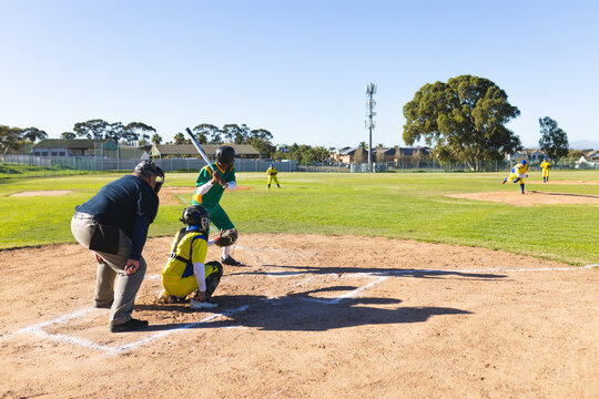 Mature male batter standing ready to swing bat in chalked batter's box on community baseball field