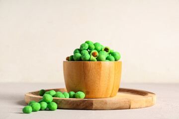 Bowl with wasabi coated crunchy peanuts on light background