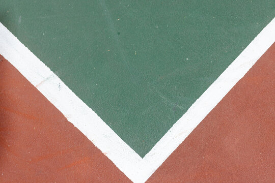 White V-shaped boundary line running across court, dividing reddish-brown and dark green sections