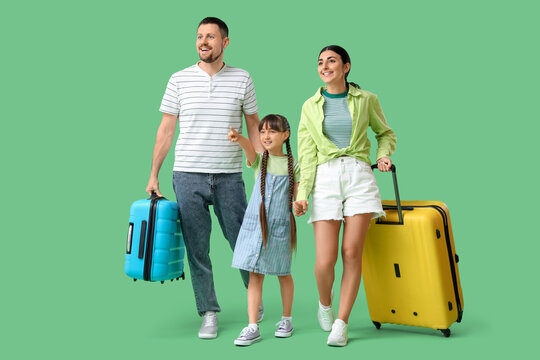 Family of tourists with suitcases walking on green background