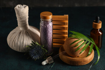 Beautiful spa composition with bottle of sea salt and herbal bag on black grunge background, closeup