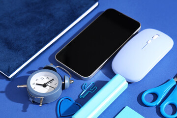 Composition with modern mobile phone and school supplies on blue background