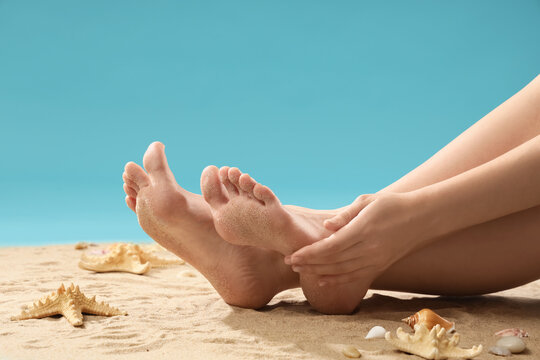 Legs of young woman on beach sand against blue background