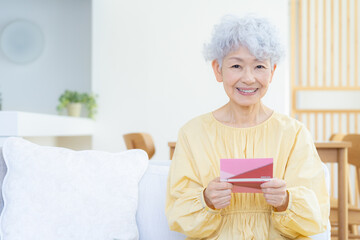 観葉植物に水をやるシニアの女性