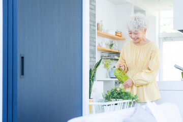 観葉植物に水をやるシニアの女性