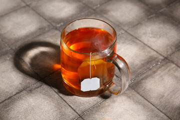 Cup of hot tea on grey tile background