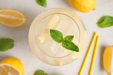 Glass of drink with ice cubes, mint leaves and lemon slices on white background