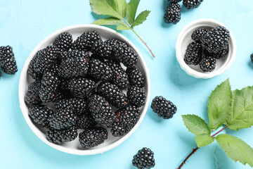 Bowls with ripe blackberry on blue background, closeup