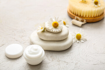 Composition with spa stones, chamomile flowers and jar of cosmetic product on grey grunge background, closeup